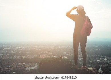 Traveling women are standing on the top of the hill overlooking the city of the evening - Powered by Shutterstock