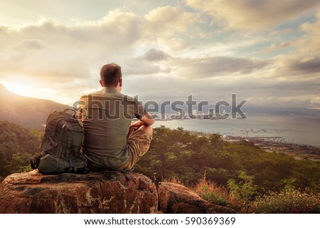 Traveller with backpack sitting on top of mountain enjoying view coast a modern city Vietnam, Nha Trang. Traveling along mountains and coast, freedom and active lifestyle concept