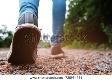 Traveller feet in sneakers surrounded at natural beauty, concept travel, color of vintage tone and soft focus.