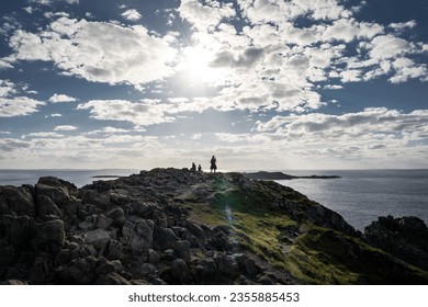 Traveller taking a picture with a cell phone on a rocky shoreline overlooking the Atlantic Ocean in Newfoundland Canada. - Powered by Shutterstock