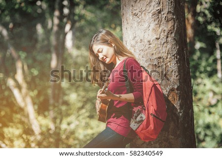 traveller woman  playing acoustic bass guitar sitting on the area forest 