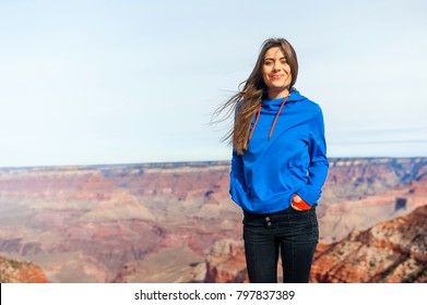 Traveller woman stands on the peak of stone at Grand Canyon viewpoint, Arizona, USA, smiling at camera in a sunny day. - Powered by Shutterstock