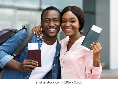 Travellers Couple. Happy Black Man And Woman With Passports And Flight Tickets In Hands Posing To Camera Near Airport Building, Cheerful Smiling African Spouses Ready For Vacation Travel, Closeup