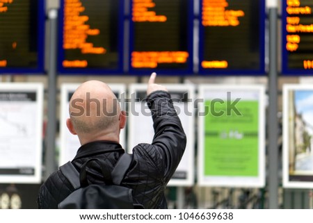 Travellers looking at departure board in a railway station.