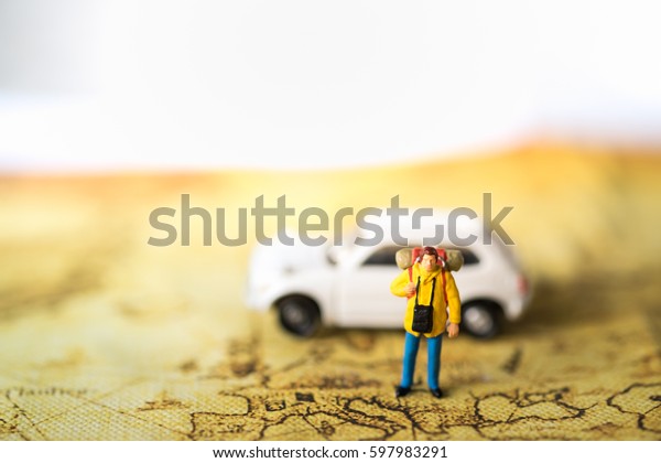 Travelling concepts. Traveler\
miniature mini figures with backpack standing on map with white car\
model