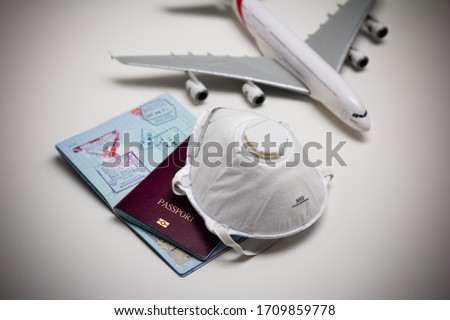 Travelling during corona virus epidemic. Passport and protective face mask respirator. Coronavirus and travel concept. Travelling with face mask. Corona virus prevention. Flights cancelled. Stay Home.