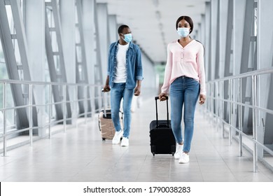 Travelling During Pandemic Concept. Black People In Masks Walking With Luggage At Airport Terminal, Copy Space