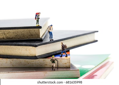 Travelling And Education Concepts. Group Of Miniature People Mini Figures With Backpack 
 Walking And Climbing On A Mountain Of Textbooks