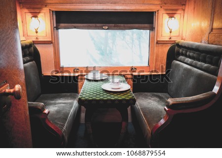 Travelling inside a luxurious vintage train carriage, private room with window view. Tea set served on table