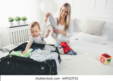 Travelling with kids. Happy mother with her child packing clothes for their holiday