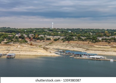 Travis Lake near Austin Texas during a drought with the waterline way down - view from above with marinas and buildings and a water tower on shore under stormy sky