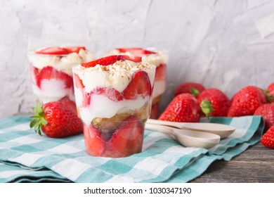 trawberry tiramisu, trifle, custard dessert in a glass with fresh strawberry ,chamomile on a wooden background