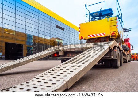 Trawl transport special machines. Loading of special equipment on the tow truck with the help of ladders. Aluminum ramps for vehicles. Trawl with aluminum ramps. Transportation of oversized cargo.