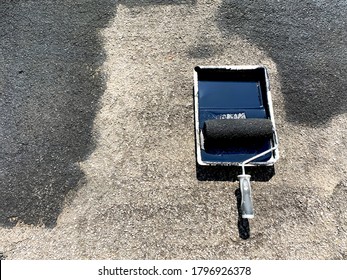 Tray Of Black Paint With A Roller Being Used To Seal A Tarmac Driveway