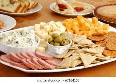 A Tray Of Cheese, Crackers And Dips On A Table With Baked Party Foods