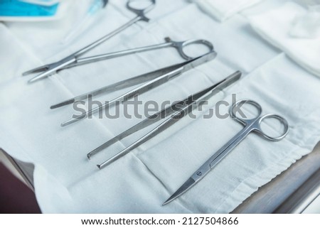 A tray containing medical tools - forceps, toothed forceps, iris scissors,syringe, sutures, and bandages. Treatment of major laceration or other wounds at the Emergency room of a hospital.
