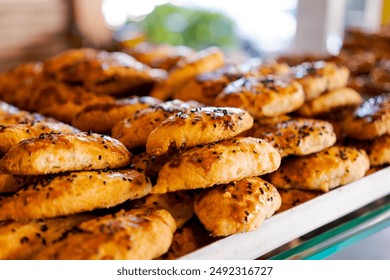 A tray filled with freshly baked pastries topped with black sesame seeds. Warm and inviting background. Bakery concept - Powered by Shutterstock