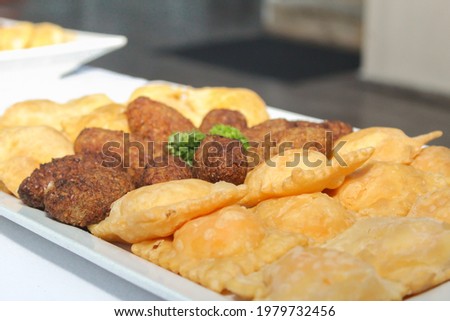 tray of food with empanadas, low calorie fried chicken quipes on a white tray on a table [[stock_photo]] © 