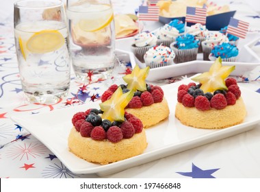 Tray Of Fresh Angel Food Fruit Cakes With Raspberry, Blueberry, And Star Fruit. Muffins On 4th Of July In Patriotic Theme In Background. 