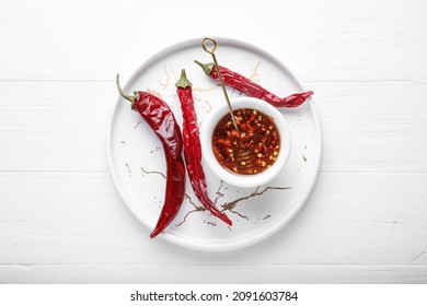 Tray with hot honey and dry chili peppers on light wooden background - Powered by Shutterstock