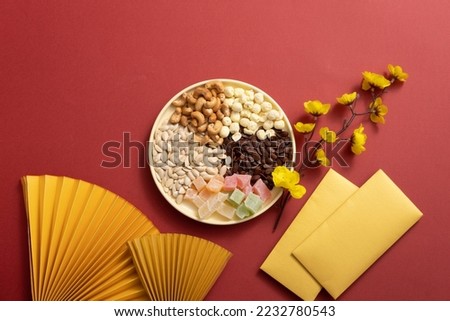 Tray of nuts and candy on Chinese new year background in Japanese style, Chinese traditional new year decoration with food, apricot blossom and lucky money. 
