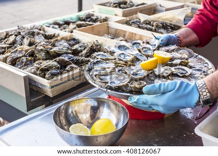 Tray of opened fresh oysters on half shell on ice with lemon in a street of Bordeaux, capital of Aquitaine. France.