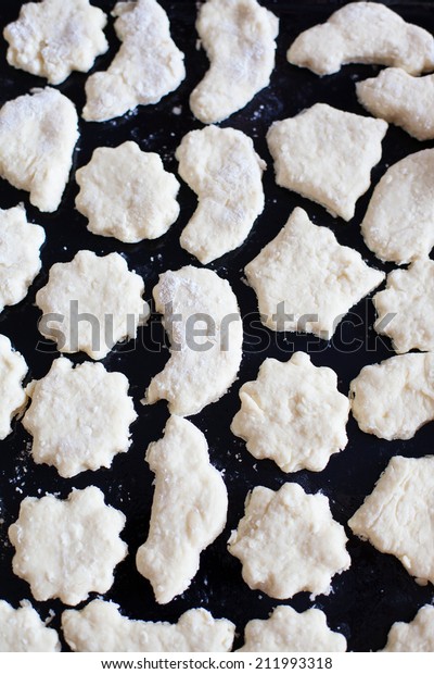 Tray of raw cookie dough of diffe?ent shapes\
flowers, cars, feet