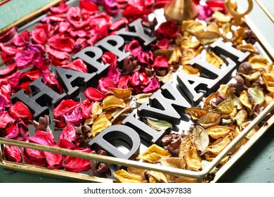Tray with text HAPPY DIWALI and flower petals on color background