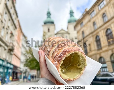 trdelnik, traditional old Bohemian sweet pastry made of yeast dough. Trdelnik is unique cinnamon sugar pastry found throughout Prague, Czech republic. selective focus on dessert over city landmarks