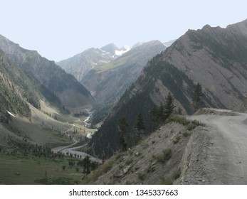 Treacherous Road In Rugged Mountainous Terrain With Rivulet Running In Parallel