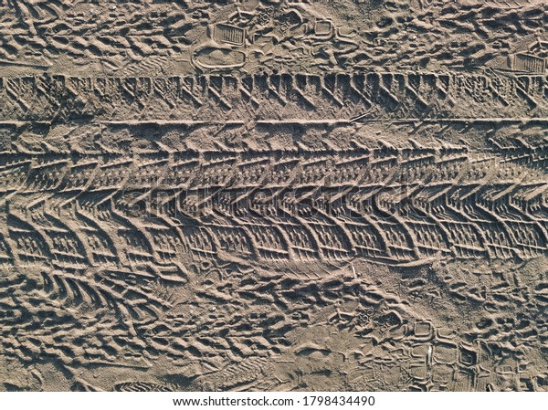 Tread marks from car and bicycle wheels on a\
dirt road made of sand. View from\
above.
