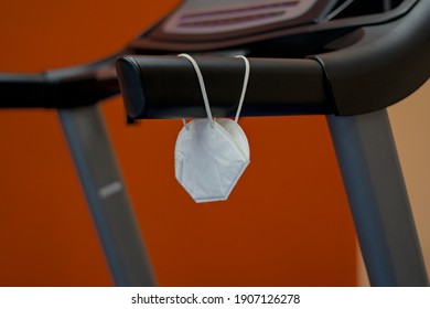 Treadmill goes unused with used mask hanging from handle as gym closed due to pandemic lock down covid 19 precautions. - Shutterstock ID 1907126278