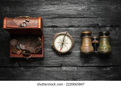 Treasure chest with coins, compass and binoculars on the old wooden table flat lay background. Pirate concept background.  - Shutterstock ID 2220065847