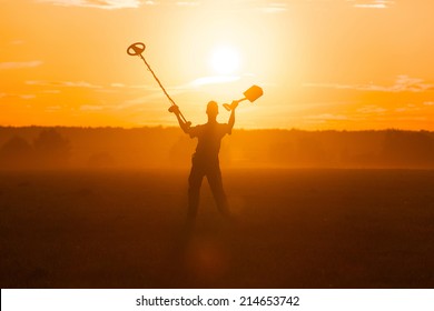 Treasure Hunter With Metal Detector In The Field On The Sunset