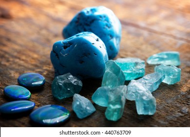 Treasure hunting. Mining for gems. Blue gems on rustic wooden table. Blue Turquoise, blue opals and apatite stones on a wooden table. Focus on large turquoise stone. Shallow depth of field. - Powered by Shutterstock