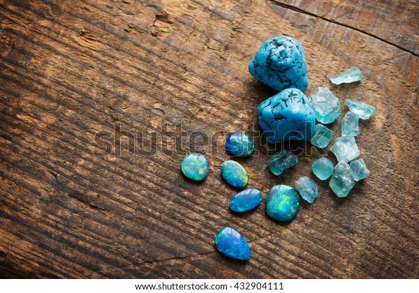 Treasure hunting. Mining for gems. Blue\
gems on rustic wooden table. Blue Turquoise, blue opals and apatite\
stones on a wooden table. Shallow depth of\
field.