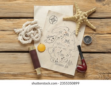 Treasure map with golden pirate amulet, smoking pipe and spyglass on brown wooden background