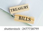 TREASURY BILLS text on wooden block with notebook on a chart background