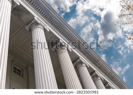 Treasury Building Ionic columns rise diagonally beneath textured clouds in Washington DC.