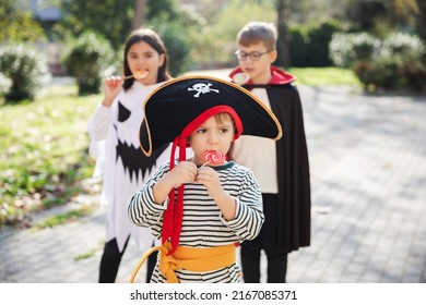 Treat or trick. Happy kids wearing carnival costumes of vampire, pirate and ghost celebrating Halloween and eating candies and lollipop. - Powered by Shutterstock