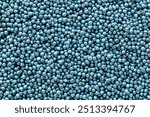 Treated rapeseed with blue coating, background, texture, top view. Encrusted rapeseed ready for sowing. Background of treated rapeseed, blue color, texture, top view.