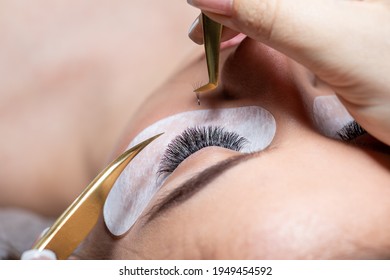 Treatment beauty procedure of upgrade Eyelashes Extension with tweezers Woman Eyes with long extended lashes closeup