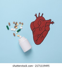 Treatment Of Cardiovascular Disease Concept. Paper Cut Anatomical Heart With Stethoscope And Pills On A Blue Background. Top View