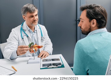 Treatment of gallbladder diseases and cholelithiasis. Gastroenterologist doctor showing gallbladder on anatomical pancreas model for male patient during consultation in medical clinic