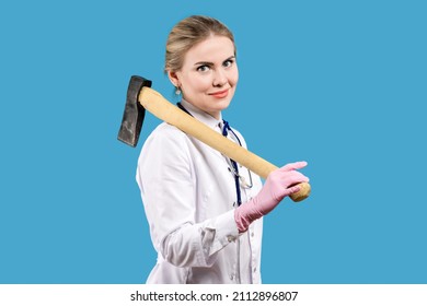 Treatment. Hospital. A Woman Doctor In A White Coat And With A Stethoscope Holds An Ax In Her Hands On A Blue Background. Therapist. Joke. Humor.