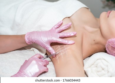 Treatment of hyperhidrosis. in the cosmetologist's office, female hands in pink gloves inject a young woman in the armpit. healthy body concept, self-care. stop sweating and bad smell