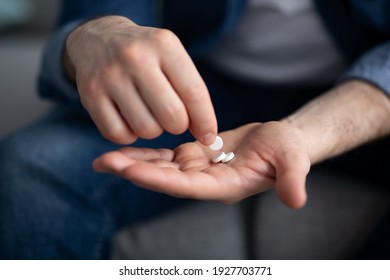 Treatment, medicine, medication, pills, vitamins, supplements concept. Unrecognizable man holding couple of pills on his palm, cropped. Closeup of male hands with medicine