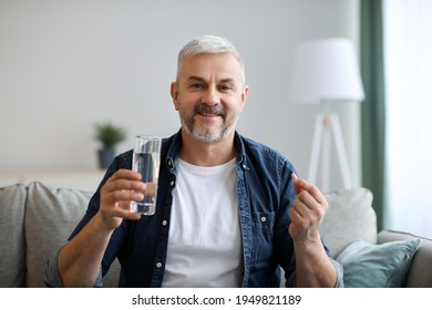 Treatment, medicine, medication, pills, vitamins, supplements concept. Smiling senior man with glass of water taking pill. Closeup of mature grey-haired man with medicine, copy space - Powered by Shutterstock