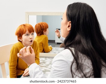 Treatment of stuttering in children. Speech and language therapist doing articulation and breathing exercises with boy patient - Powered by Shutterstock