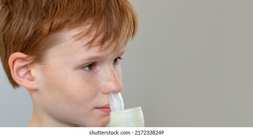 For Treatment, Use A Nebulizer And An Inhaler. The Child Inhales A Nasal Inhaler Through The Nozzle. Face Close-up